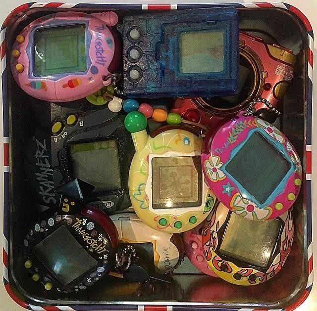 Colorful collection of retro Tamagotchi virtual pet keychain toys piled in a tray