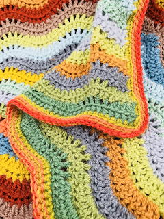Colorful ripple crochet blanket with wavy stripes in rainbow colors