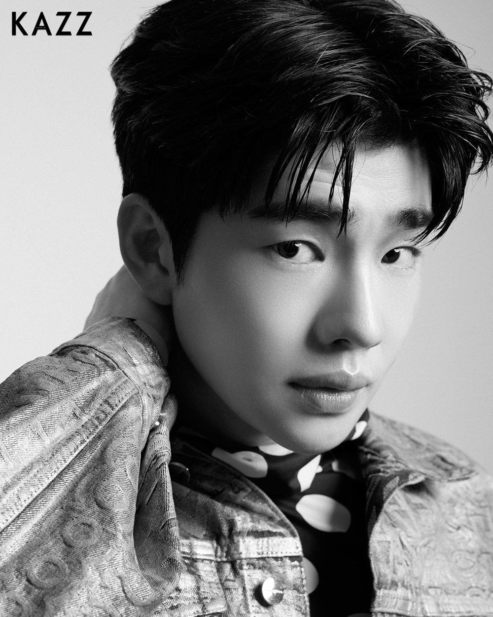 Black and white close-up portrait of a young Asian man with swept bangs wearing a patterned jacket