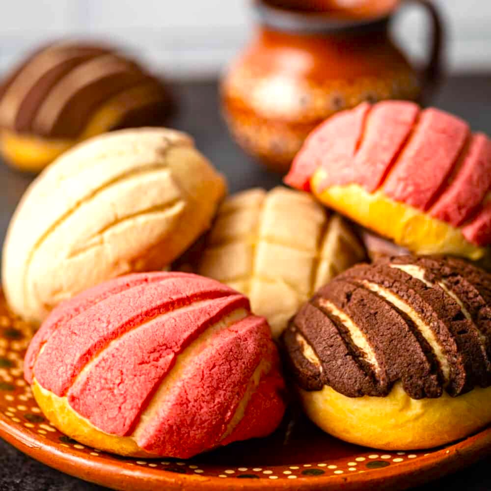 Close-up of assorted conchas sweet breads on a ceramic plate