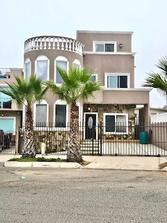 Modern three-story beige house with palm trees and arched balcony