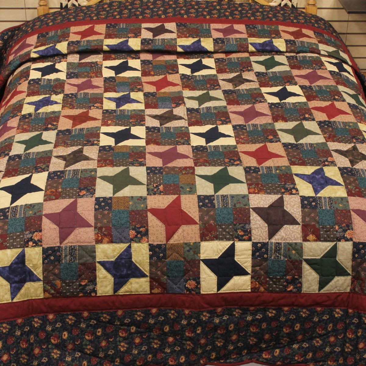 Traditional Amish-style patchwork quilt with star pattern in warm colors on wood floor