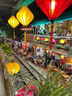 Colorful lanterns hanging over Hanoi train street with cafes and diners at night