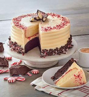 Peppermint bark cake with a slice on a plate beside candy canes and a cup