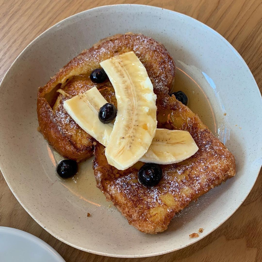French toast topped with banana slices and blueberries on a plate with syrup