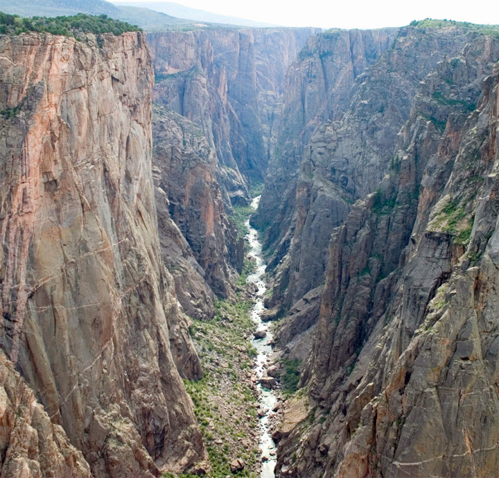 Aerial view of a deep canyon with towering rock walls and a river flowing through the bottom