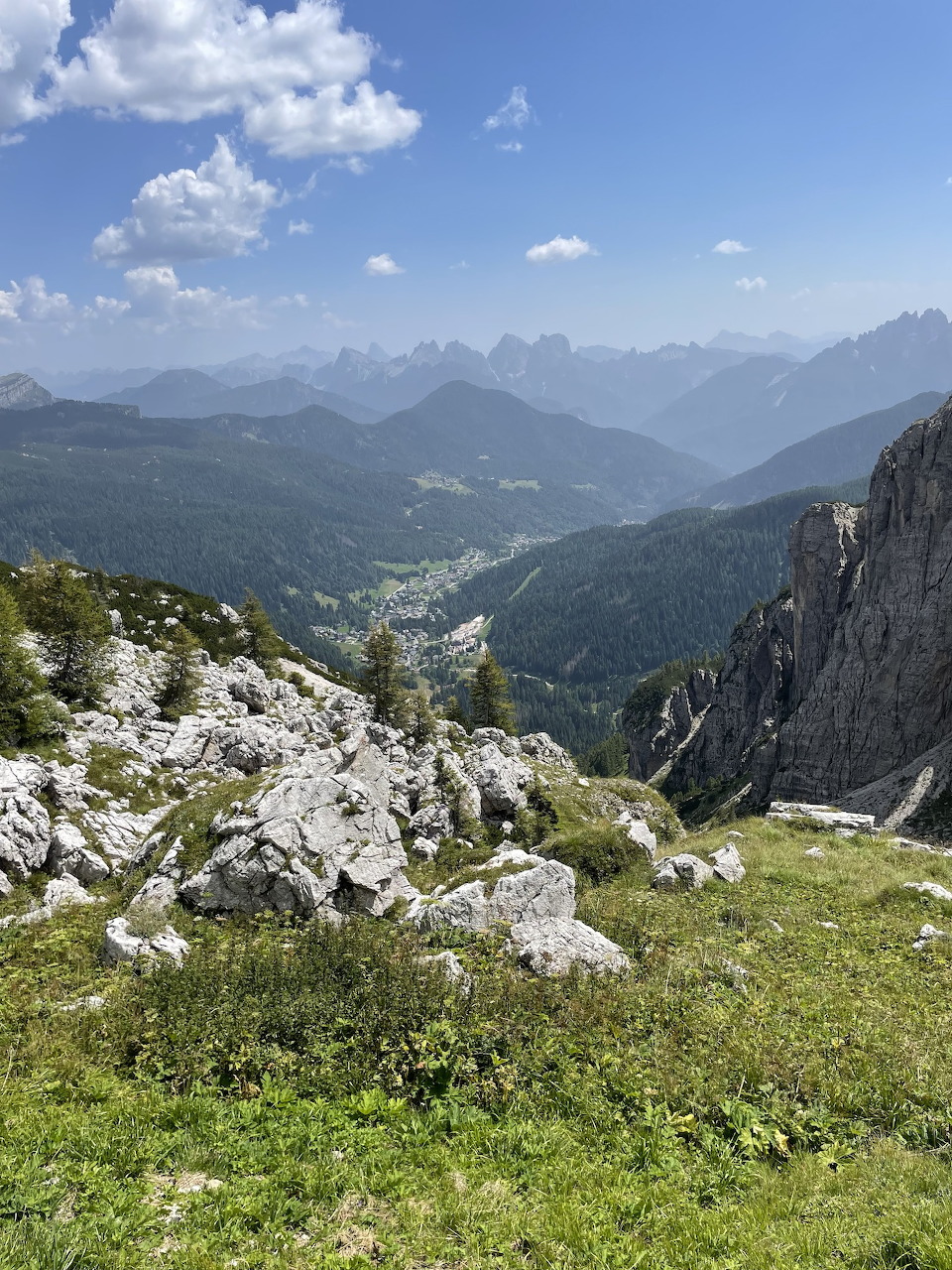 Rocky hillside overlooking a green valley and Dolomite mountain peaks in Italy