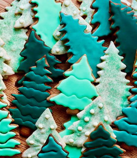 Green and teal frosted Christmas tree cookies with white pearl decorations and chocolate drizzle