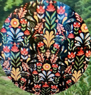 Circular embroidered design with vibrant folk art flowers on black fabric