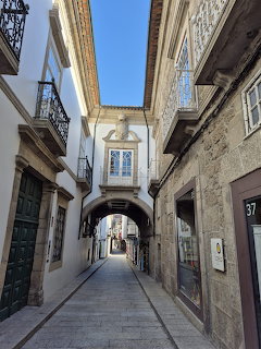 Narrow street with stone buildings and arched passageway in a historic Portuguese town under blue sky