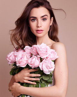 Woman with dark brown hair holding a large bouquet of pink roses against a beige background