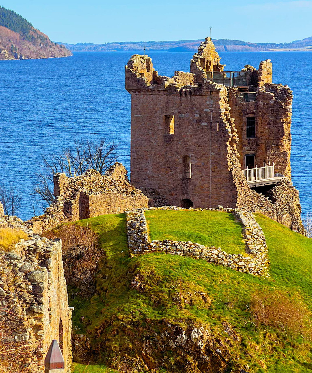 Ruins of Urquhart Castle on a green hill beside Loch Ness, Scotland