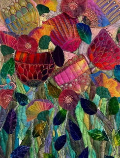 Colorful textile art with layered fabric flowers featuring detailed stitching and vibrant patterns