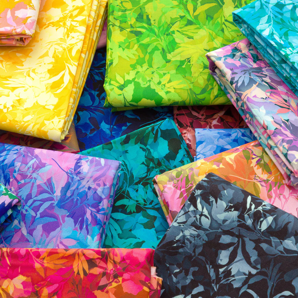 Overlapping colorful patterned fabrics with floral and tropical designs in bright yellow, green, blue, and pink hues