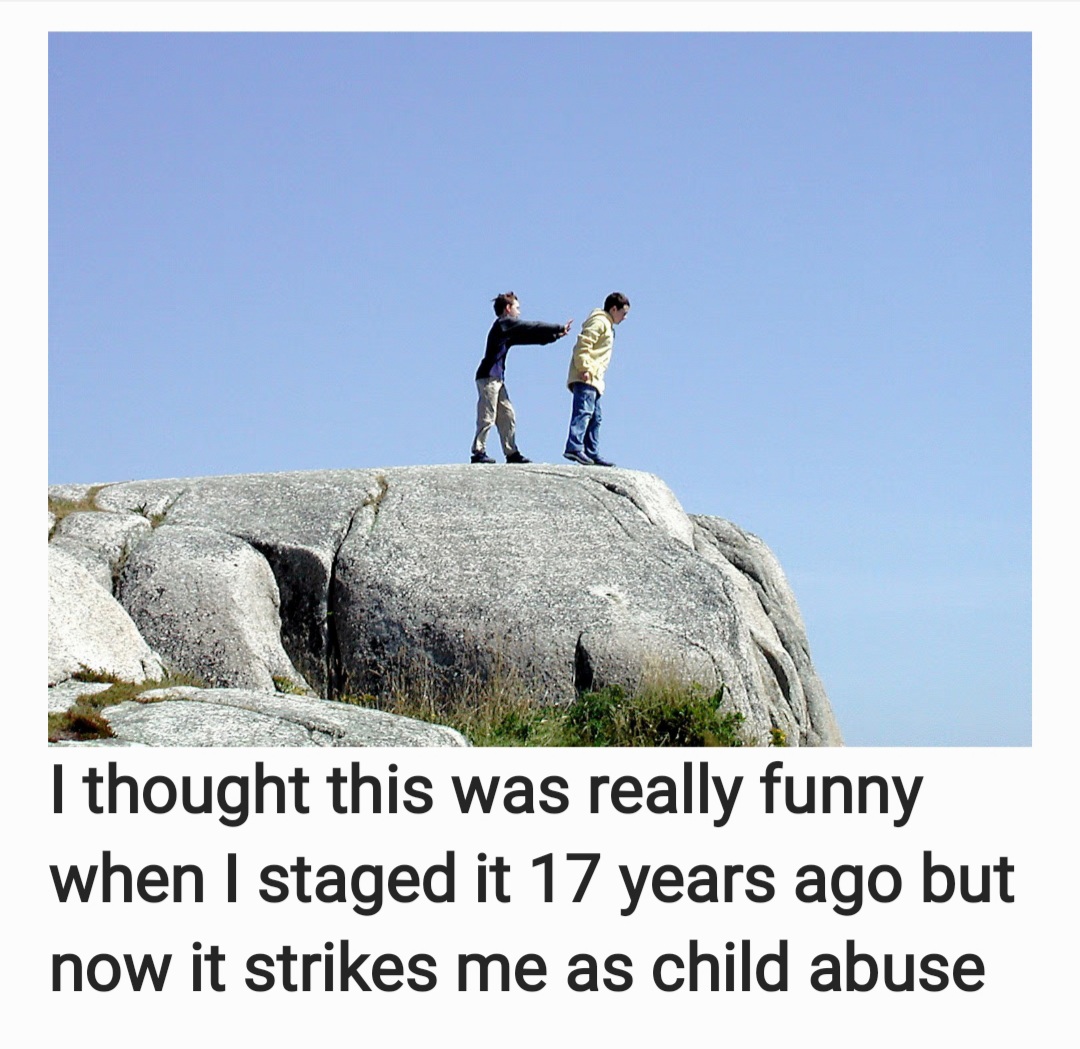 Two people stand on a large rock under a blue sky, with a caption underneath the photo.