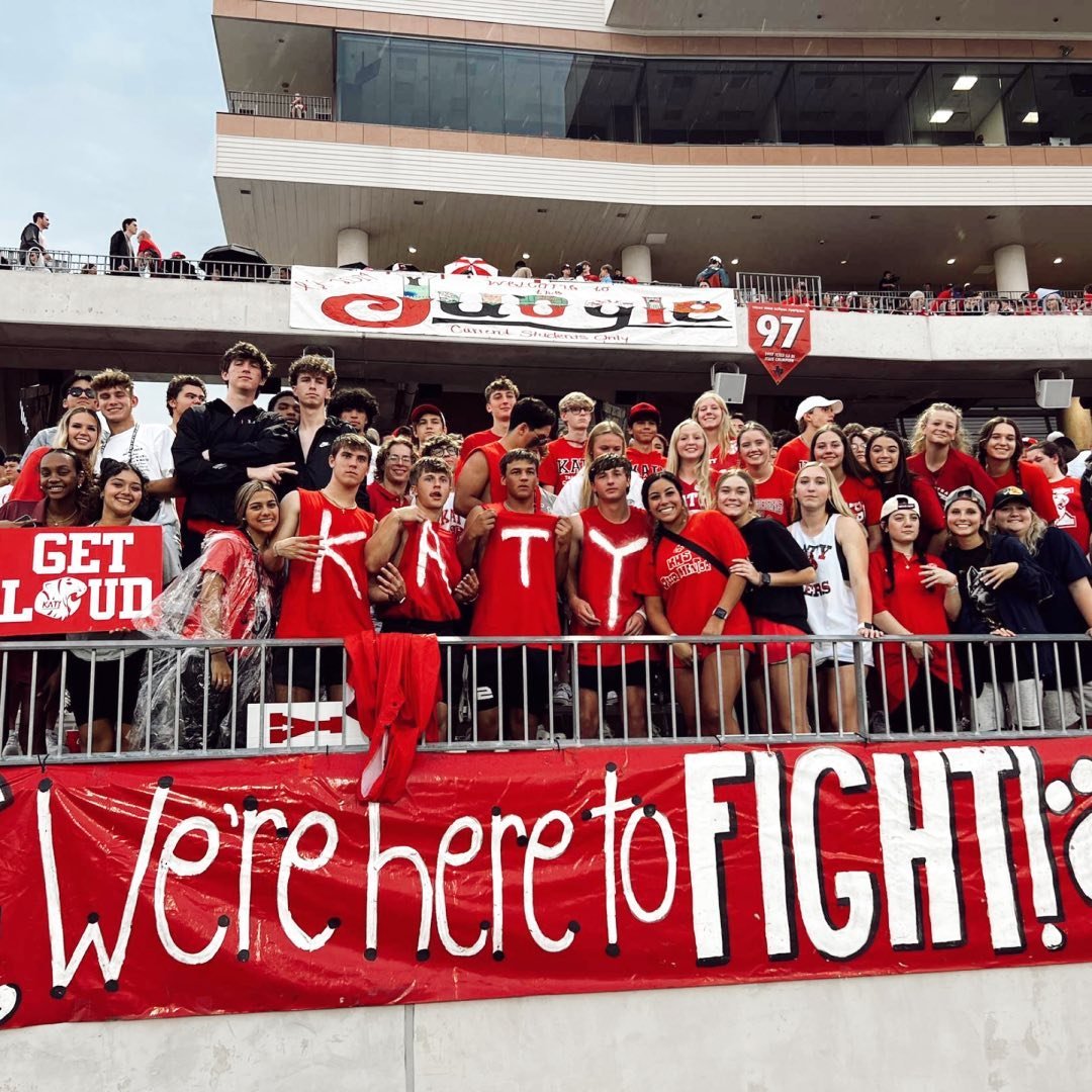 Group of soccer fans in red shirts at stadium with banner