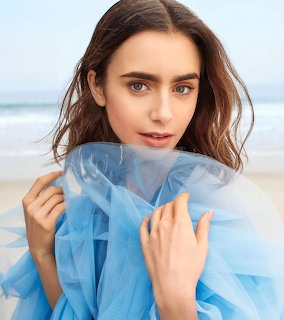 Woman in blue tulle on beach looking at camera with ocean background