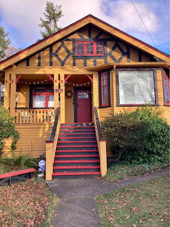 Yellow craftsman cottage with timber beams, red staircase, and front porch