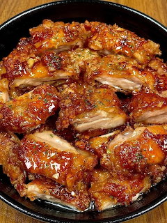 Teriyaki chicken pieces with glossy brown glaze in black skillet