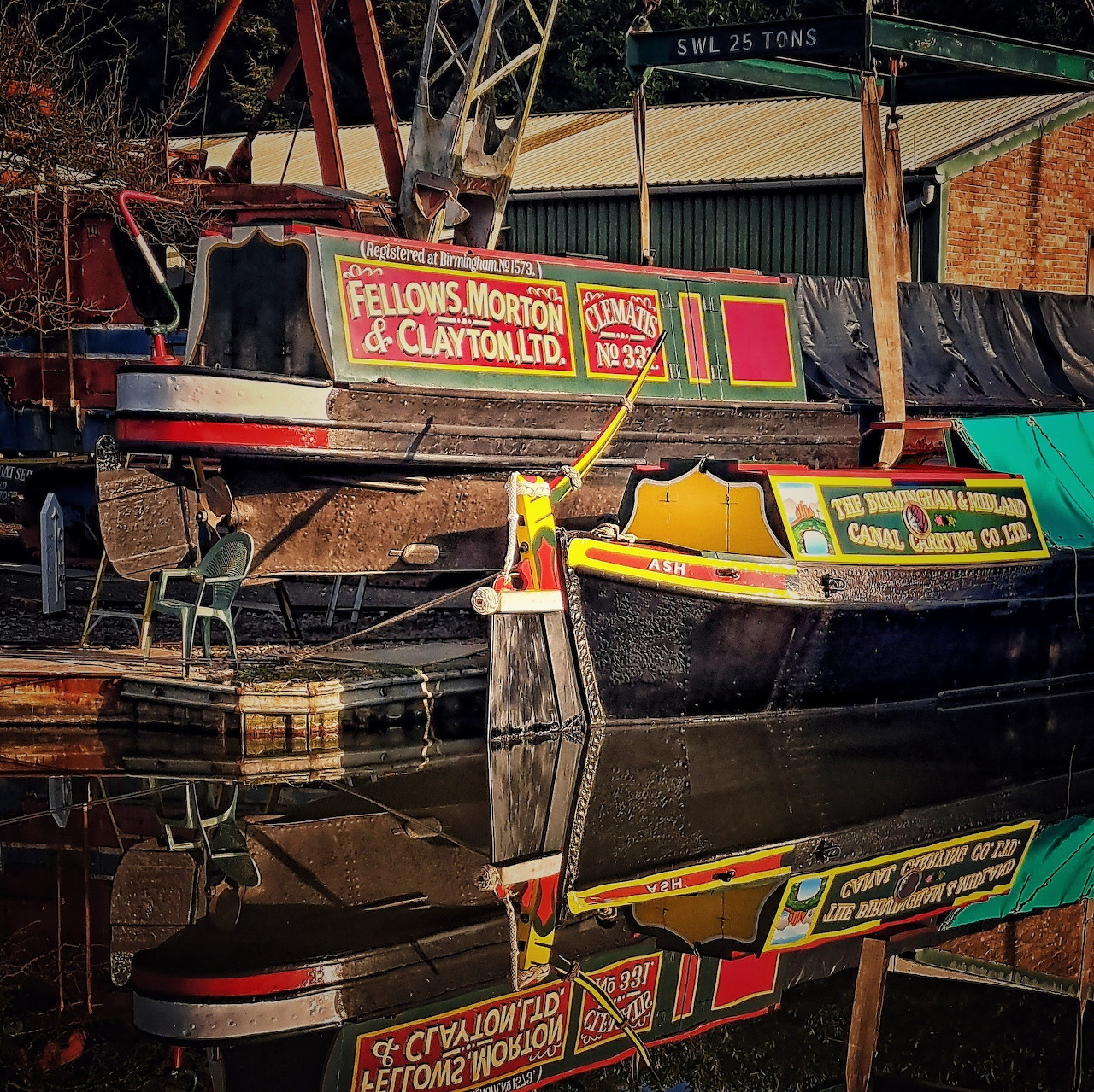 Two colorful canal boats beside still water with bright reflections