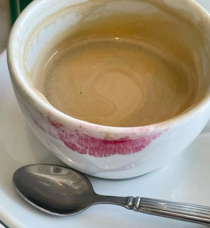 White coffee cup on a saucer with a metal spoon beside it
