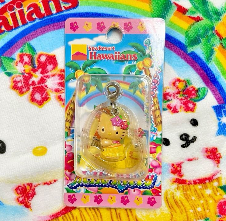 Packaged Hello Kitty keychain on a colorful tropical Hello Kitty fabric background