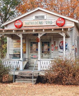 Old country grocery store with white porch railing, Coca-Cola signs, and vintage vending machines