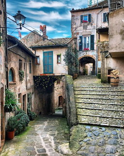 Narrow cobblestone alley with stone steps and arched passageway in an old Italian village