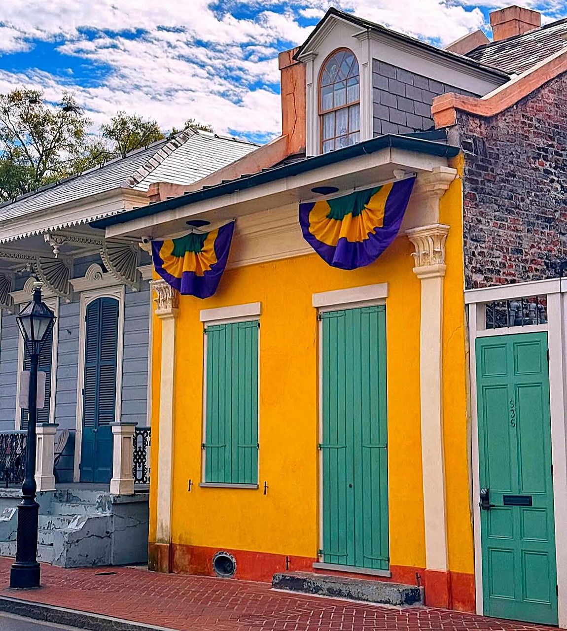 Bright yellow house with green doors decorated with purple and gold Mardi Gras bunting