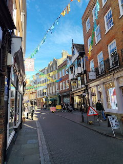 Historic Cambridge street with shops, brick buildings, and bunting overhead