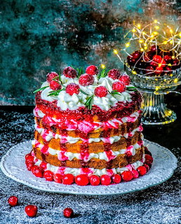 Festive cranberry layer cake with berries and cream on a silver platter