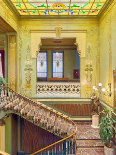 Art Nouveau staircase with stained glass skylight and ornate yellow walls