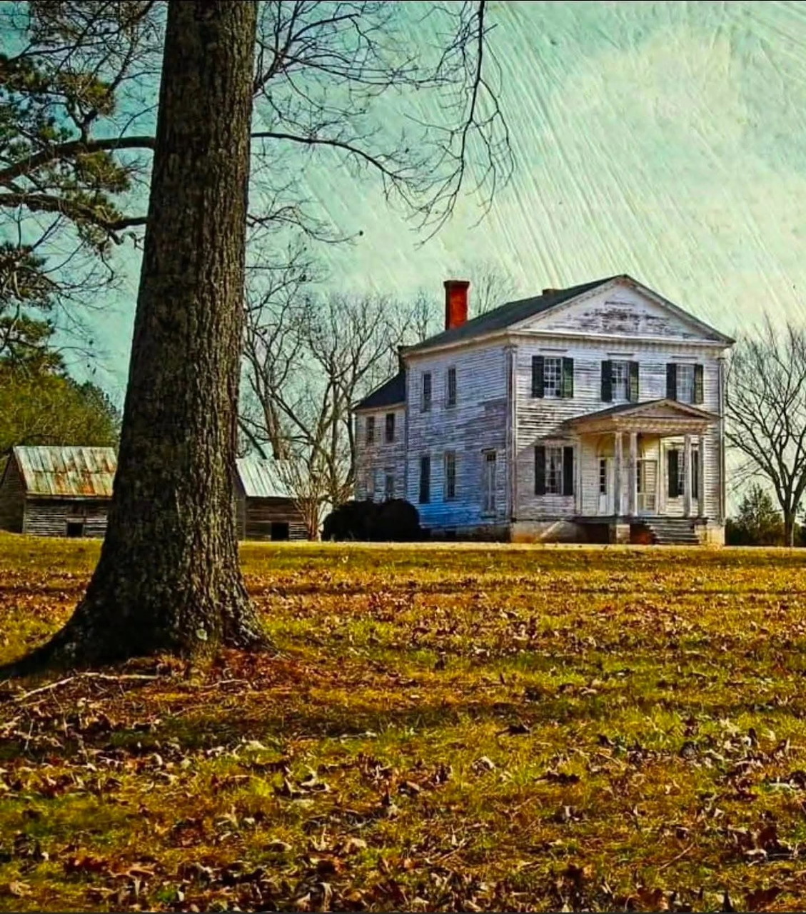 Historic white Federal plantation house with red chimney surrounded by bare trees on a grassy lawn in winter