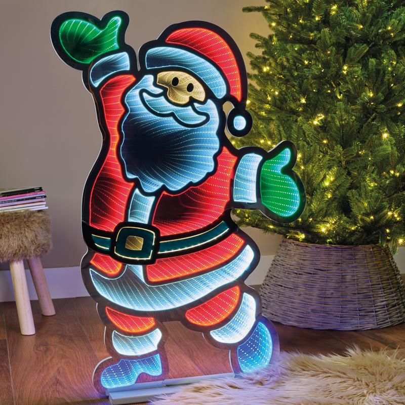 Illuminated Santa decoration standing next to a lit Christmas tree indoors