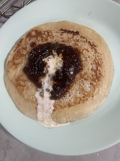 Pancake topped with jam and cream on a light blue plate