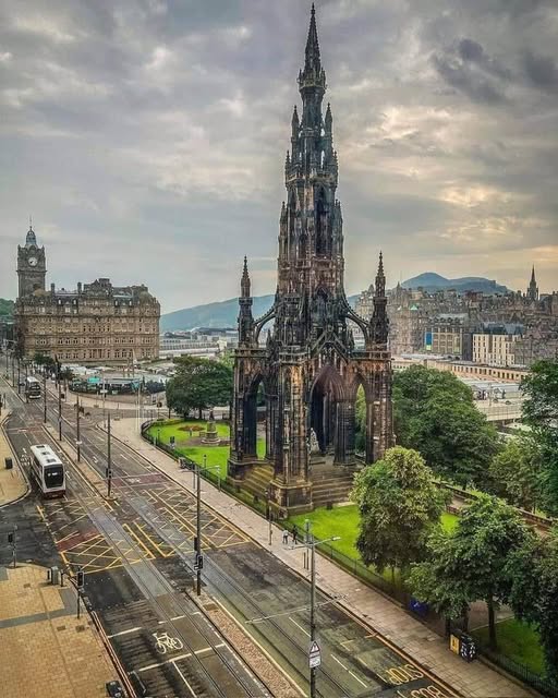 Tall Gothic monument in Edinburgh with surrounding wet streets and cloudy sky