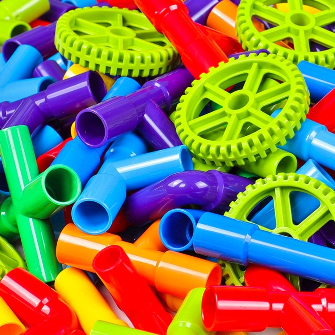 Pile of colorful plastic toy gears and tubes in neon yellow, green, purple, blue, red, and orange