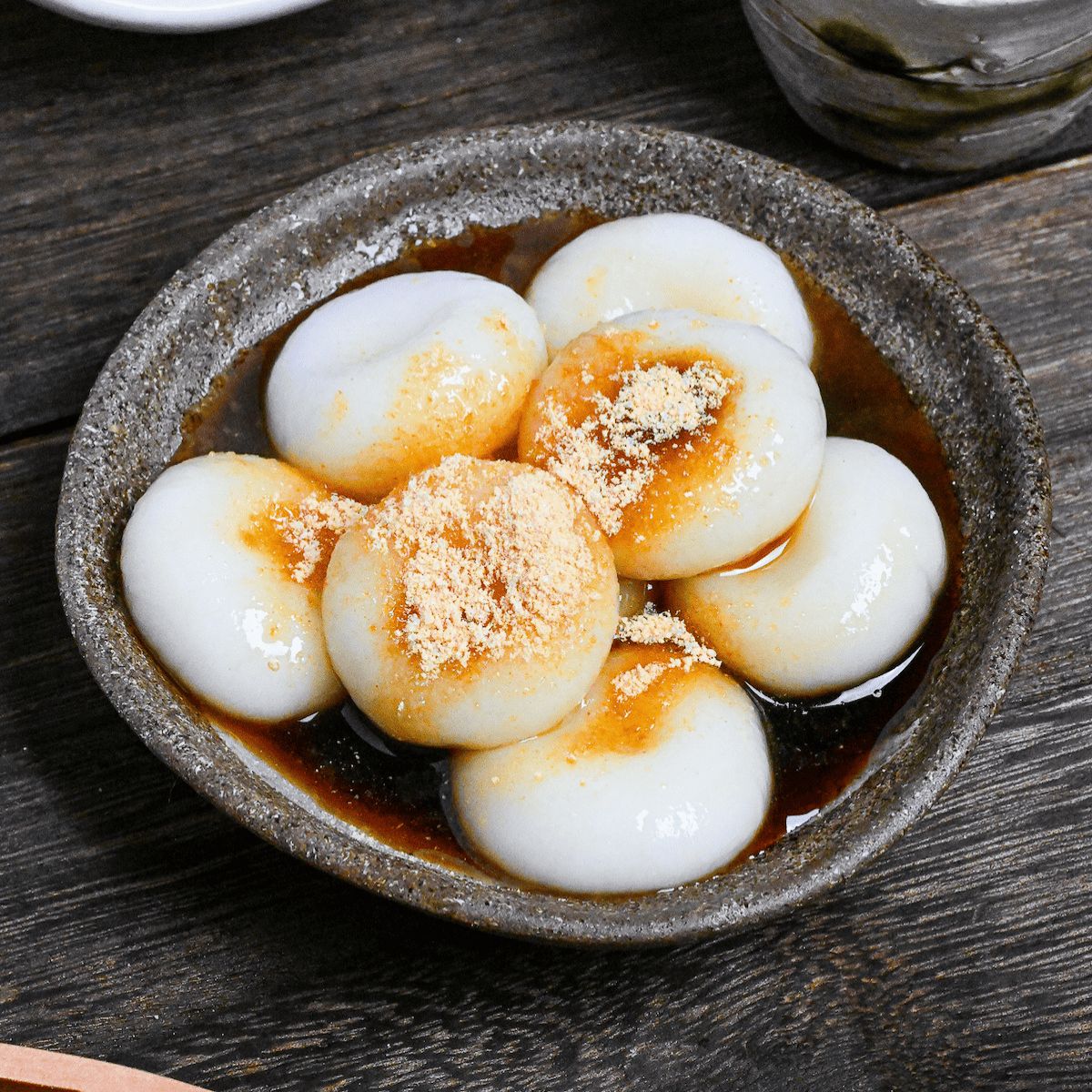Bowl of Japanese dango dumplings in dark sauce topped with powder