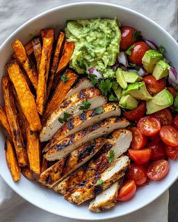 Bowl with grilled chicken, sweet potato fries, tomatoes, avocado and green sauce