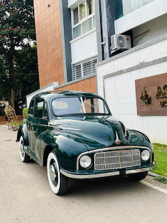Dark green 1950 Morris Minor vintage car parked in front of a residential building
