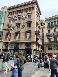 Historic building on La Rambla Barcelona with decorative spheres and pedestrians on the street