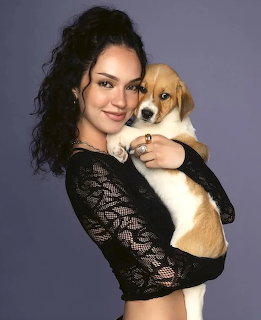 Woman in a black lace top holding a beagle puppy against a gray background