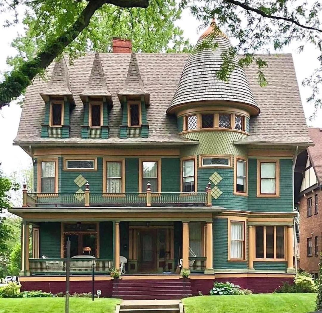 Victorian mansion with turret, wraparound porch, decorative trim, teal and cream exterior