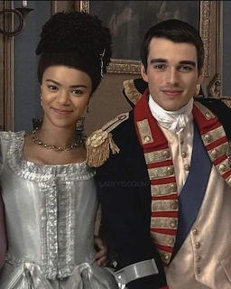 Woman and man in historical royal-style clothing posing indoors