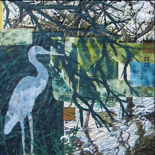 Art quilt depicting white heron with tree branches over water in blues, greens and earth tones