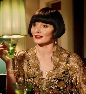 Woman in gold sequined dress with bob haircut holding green cocktail glass in vintage interior