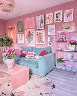 Bright pink living room with turquoise couch, colorful wall art, pink shelves, and floral arrangements