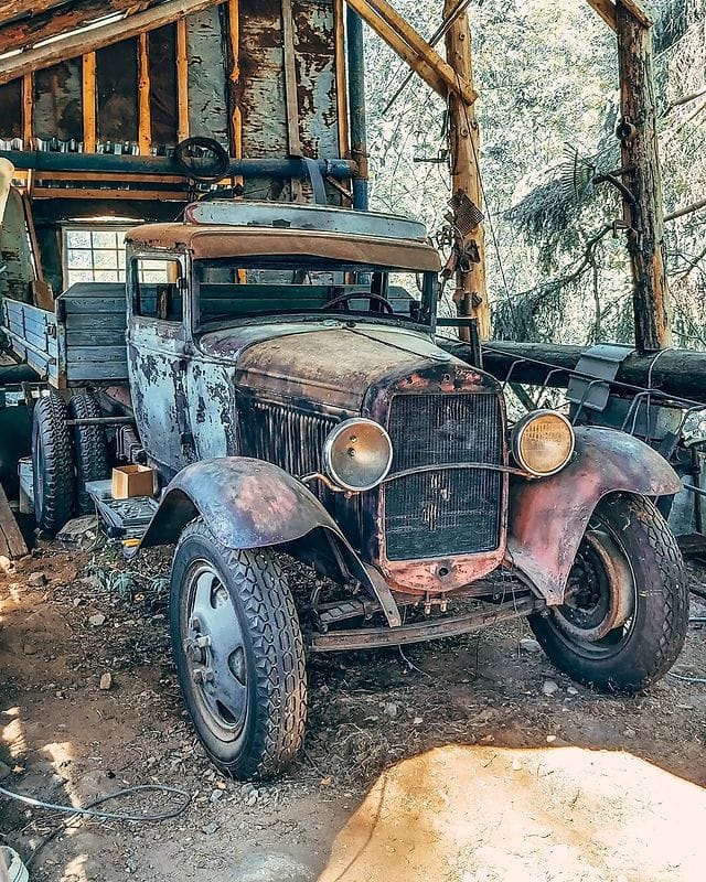 Rusty abandoned vintage Model T truck inside a dilapidated wooden barn