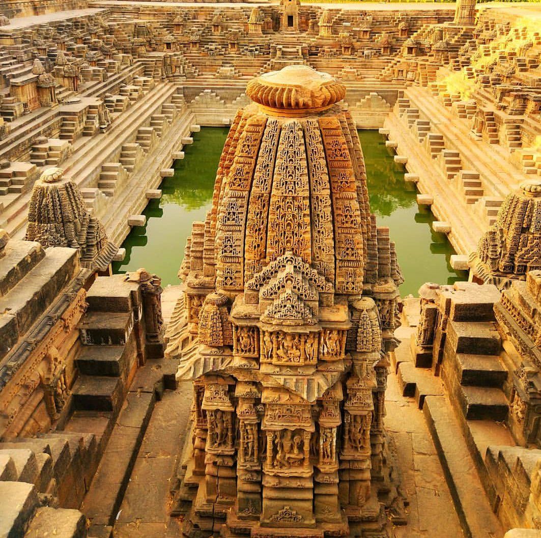 Aerial view of ancient Modhera Sun Temple complex with ornate carved stone structures and stepped water tank