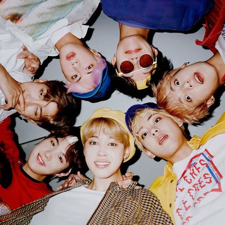 Six young people lying in a circle, looking up at the camera in colorful clothing